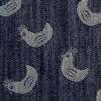 Denim textile with repeating crescent moon pattern in off-white, featuring a woven texture and striped details, labeled “denim cucu edition”.